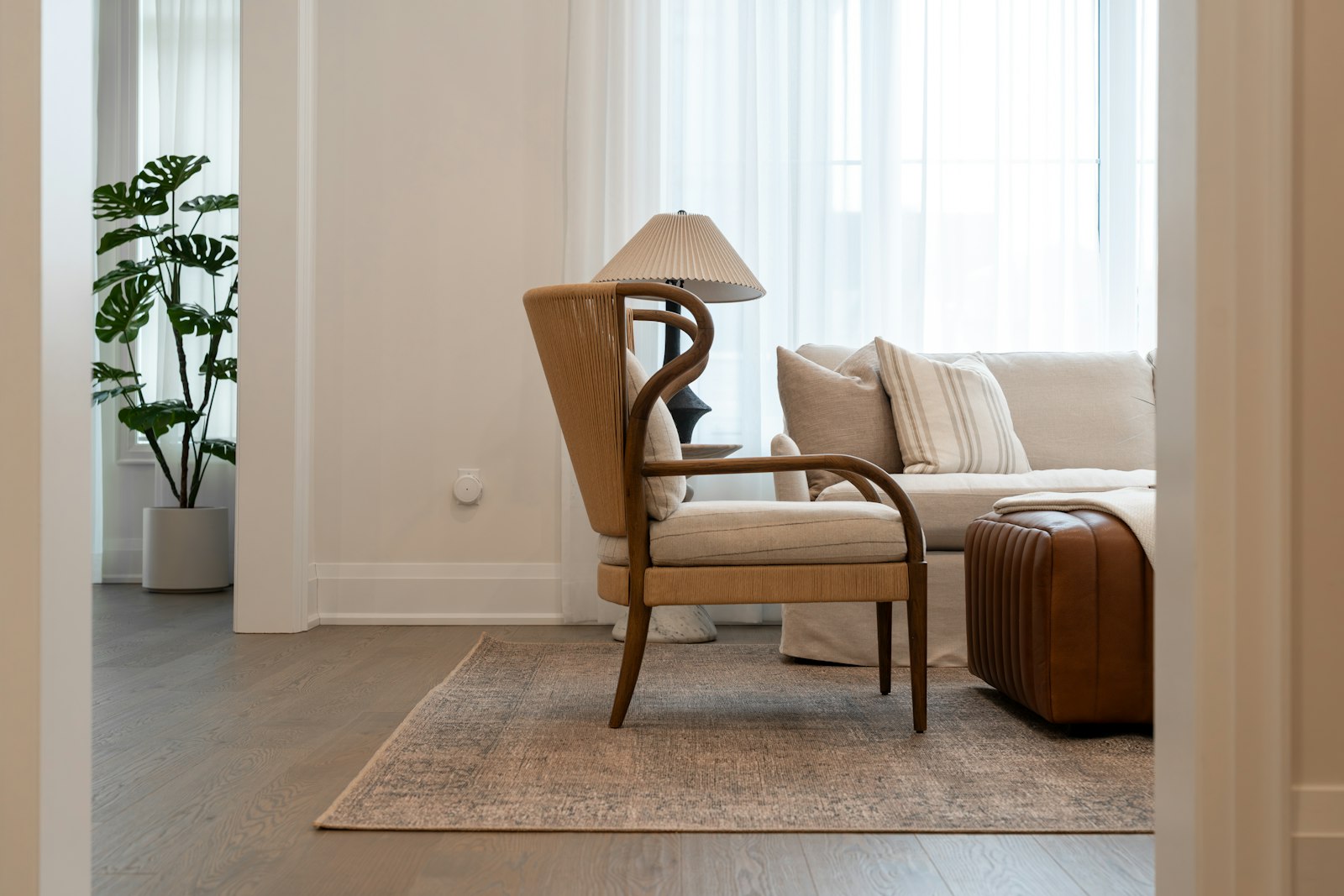 Rotan fauteuil met kussen naast een effen bank in een lichte woonkamer