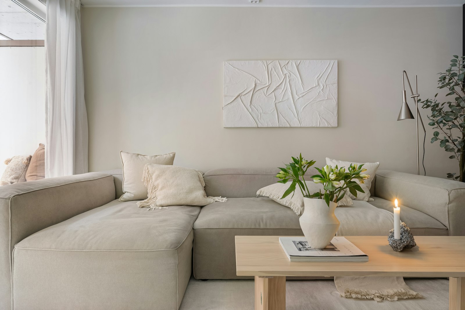 Zandkleurige bank in een lichte woonkamer met natuurlijke materialen