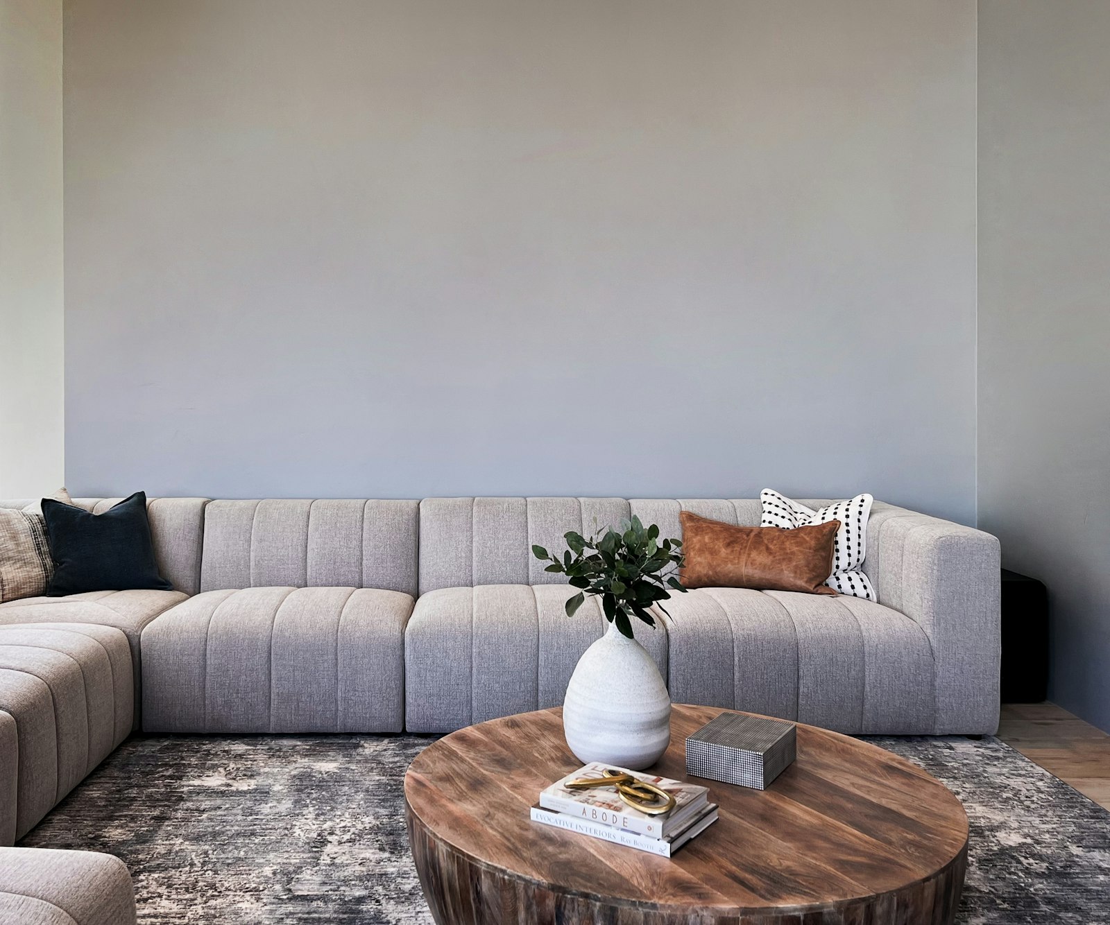 Ruime woonkamer met een U-vormige bank in beige en een lage salontafel